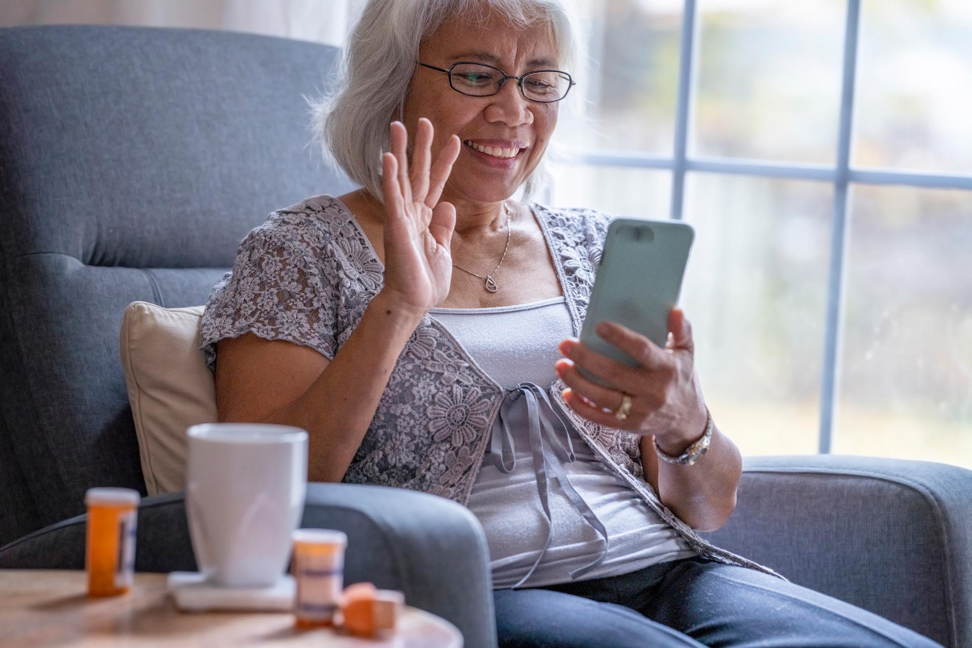 Woman sitting in a comfortable chair, participating in a Virtual Roundtable on her smartphone